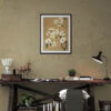 Elegant white floral art print in black frame hanging above rustic wooden desk in modern home office. Neutral taupe walls complement the warm tan background of the botanical artwork. Workspace features minimalist desk styling with vintage lamp, wooden horse figurine, small succulent plant, stacked books, and gray chair creating a sophisticated yet cozy work environment.