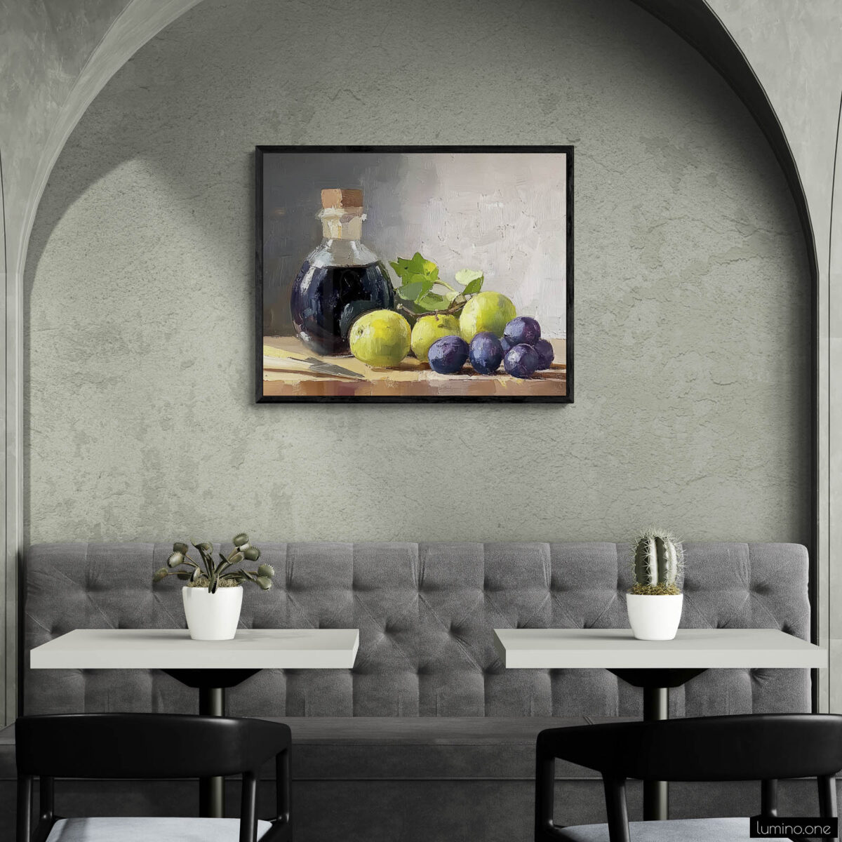 Framed still life oil painting print featuring green grapes, dark wine bottle with cork, and blue grapes arranged on wooden surface, displayed in modern cafe or restaurant with arched alcove, gray banquette seating, and white bistro tables