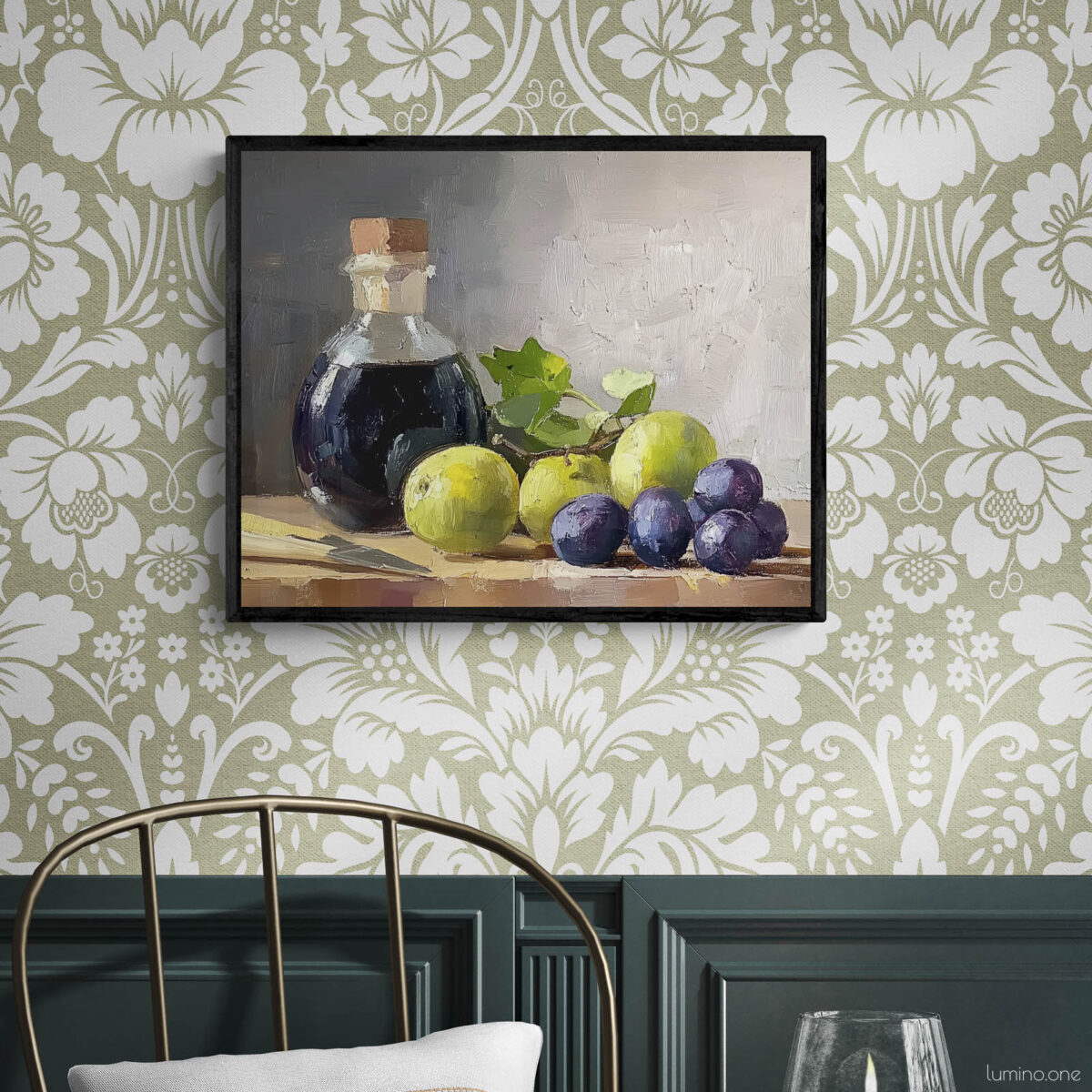 Framed still life oil painting print featuring green grapes, dark wine bottle with cork, and blue grapes arranged on wooden surface, displayed in traditional dining room with sage green floral wallpaper, dark wood wainscoting, and brass chair with round table
