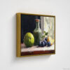 Still life oil painting framed canvas print featuring green apple, dark plums, and green glass bottle with cork arranged on white cloth, displayed in antique gold floating frame against white background