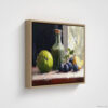 Still life oil painting framed canvas print featuring green apple, dark plums, and green glass bottle with cork arranged on white cloth, displayed in natural wood floating frame against white background