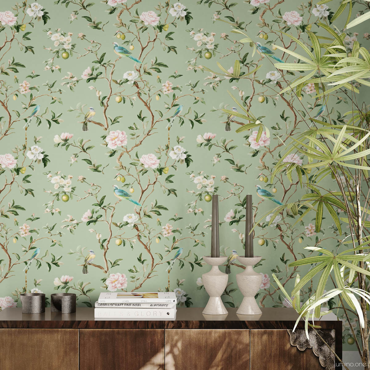 Sage green chinoiserie peel and stick wallpaper with hand-painted birds, pink peonies, and lemon branches styled with wooden credenza, white ceramic candlesticks, coffee table books, and tropical palm plant