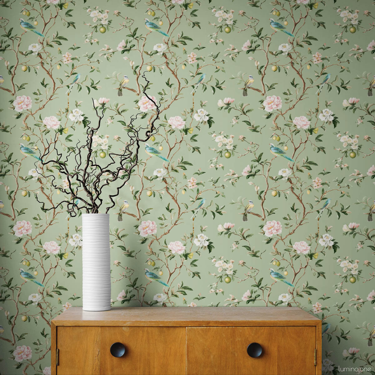 Sage green chinoiserie botanical wallpaper with hand-painted birds, pink peonies, white blossoms, and lemon branches styled with vintage wood dresser and white ribbed ceramic vase with curly willow branches