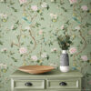 Sage green chinoiserie vintage wallpaper with hand-painted birds, pink peonies, and lemon branches styled with matching sage green dresser with black cup pulls, wooden bowl, and striped ceramic vase with eucalyptus