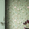 Sage green chinoiserie peel and stick wallpaper with hand-painted birds, pink peonies, white blossoms, and lemon branches next to vintage mint green door with dried burgundy flowers