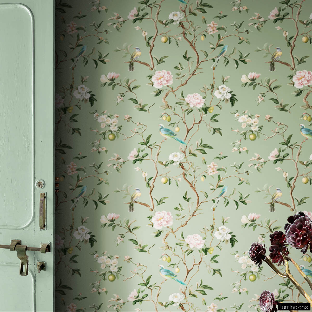 Sage green chinoiserie peel and stick wallpaper with hand-painted birds, pink peonies, white blossoms, and lemon branches next to vintage mint green door with dried burgundy flowers
