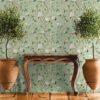 Sage green chinoiserie removable wallpaper with hand-painted birds, pink peonies, and lemon branches styled with vintage wooden console table, terracotta planters, and potted trees on tile floor