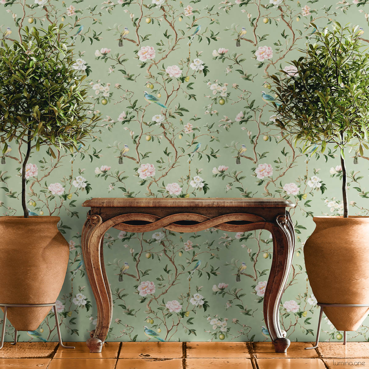 Sage green chinoiserie removable wallpaper with hand-painted birds, pink peonies, and lemon branches styled with vintage wooden console table, terracotta planters, and potted trees on tile floor