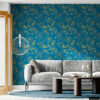 Modern living room accent wall covered in dark teal peel and stick wallpaper featuring gold botanical peony pattern, styled with a gray sofa, round wood coffee table, and gold pendant light