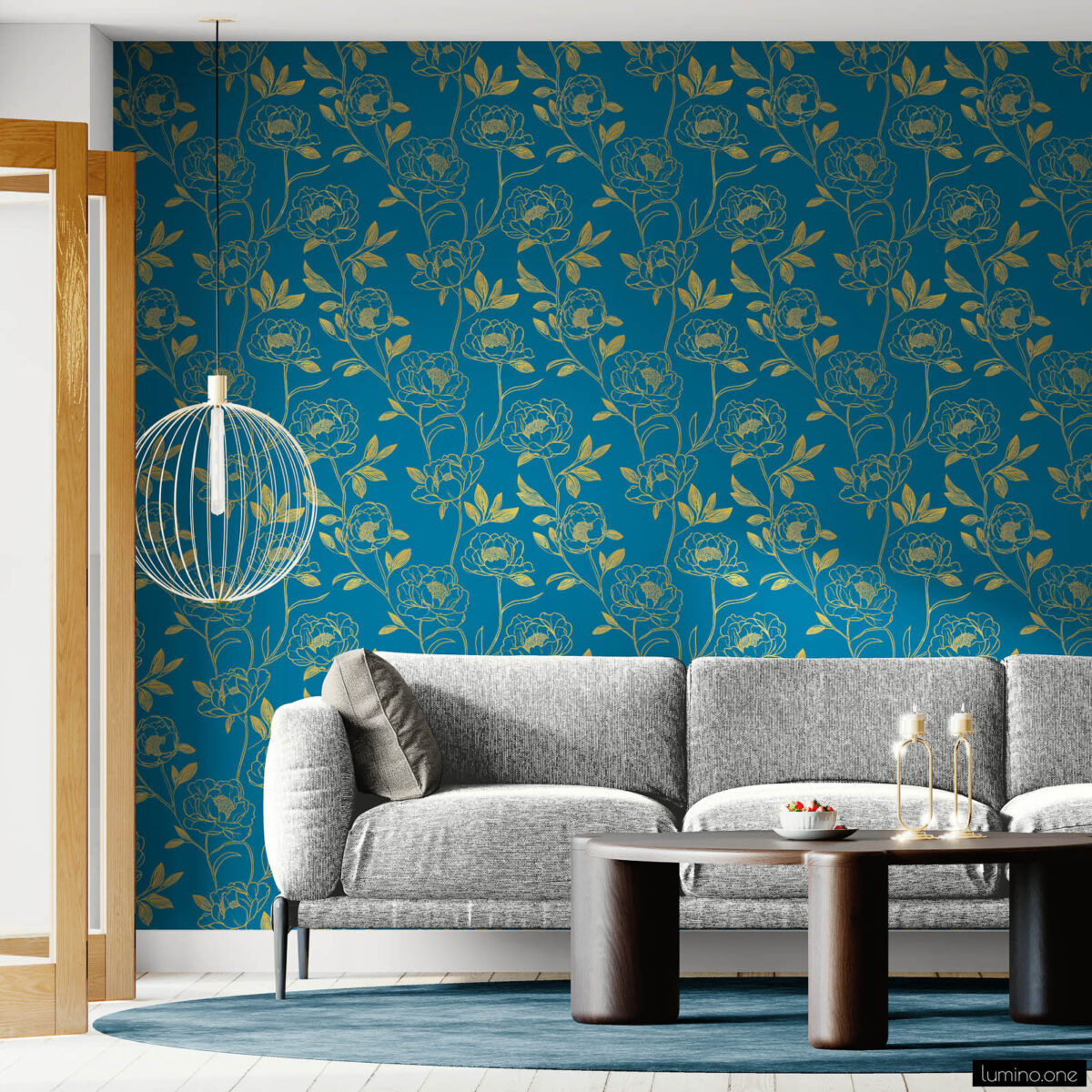 Modern living room accent wall covered in dark teal peel and stick wallpaper featuring gold botanical peony pattern, styled with a gray sofa, round wood coffee table, and gold pendant light